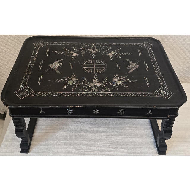 Antique Chinese bed tray finished in black lacquer and extensively decorated with hand-cut mother-of-pearl inlay. The...