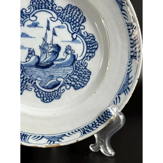 This charming faience plate is a classic example of 18th-century Dutch Delftware, distinguished by its hand-painted cobalt...