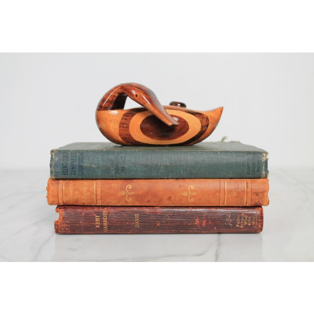 Vintage hand-carved wood duck figurine in a preening posture. It is crafted using laminated or inlaid segments of...