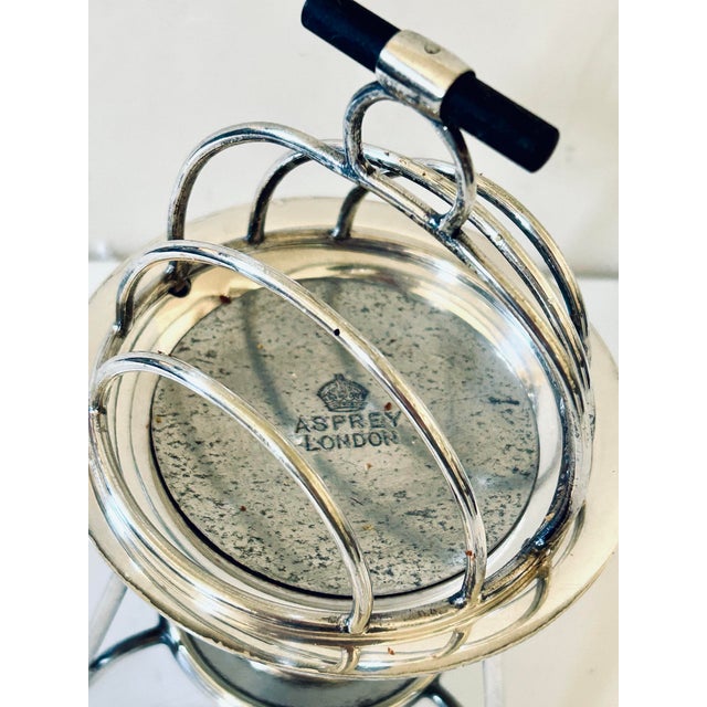 A fine and unusual silver plate Asprey & Co heated toast rack with four divisions and an ebony bar handle complete with...