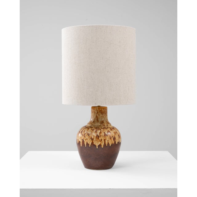 This 20th Century German brown lava ceramic table lamp showcases the rich, textural glazing that defines mid-century...