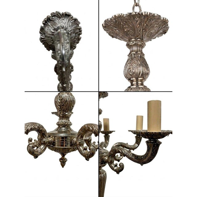 An ornate antique chandelier featuring elaborate ornamentation, sculptural curved arms, floral motifs, and a richly...