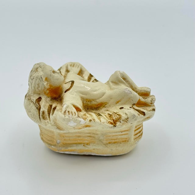 A charming Baby Jesus nativity figure in manger, crafted in chalkware/composition with a beautifully worn finish. This...