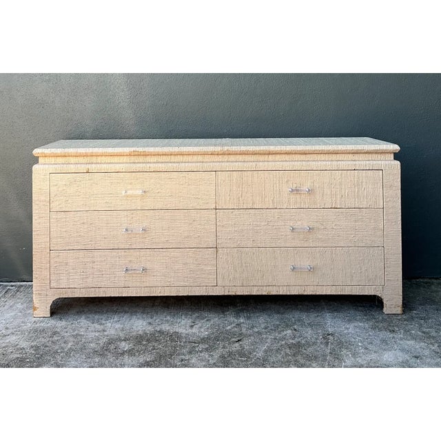 This vintage dresser combines a warm, tactile grasscloth finish with crisp Lucite handles for a distinctive mid-century...