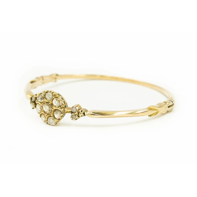 Antique Victorian 10k yellow gold bangle bracelet featuring a centrally set diamond flower with a 8 rose cut diamonds...