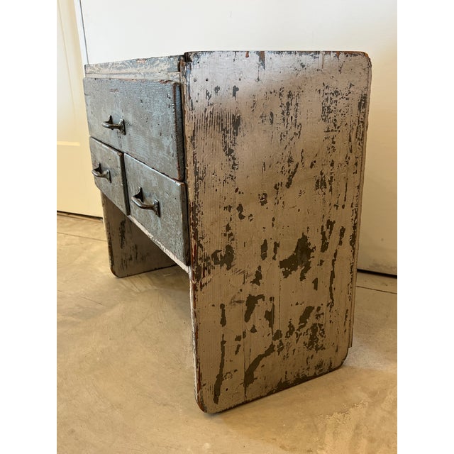 A beautifully worn early 1900s pine utility cabinet featuring an authentic, timeworn painted surface in a soft, muted...