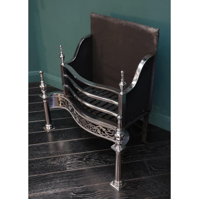 A free-standing polished steel fire grate in the Georgian form. The railed fire basket with three fire bars over an ornate...