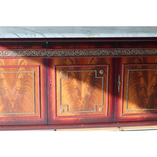 An exceptional monumental neoclassical sideboard featuring a massive one-piece marble top over a beautifully crafted flame...
