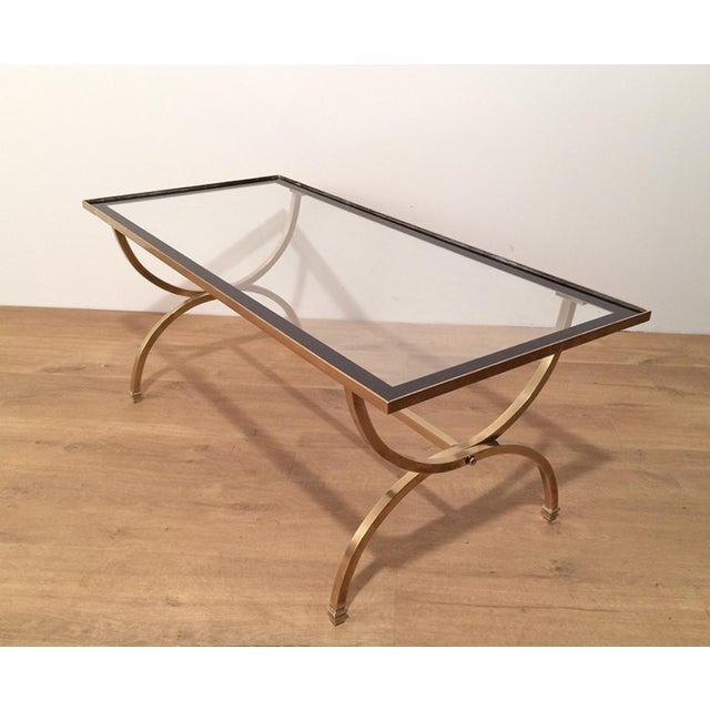 This beautiful rectangular coffee table is made of brass with a clear glass top surrounded by black lacquered edges. It is...
