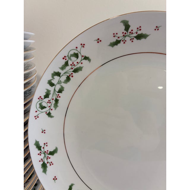 A festive vintage finds set of 24 dinner plates in the Holly Berry pattern, each decorated with a hand-painted-style holly...