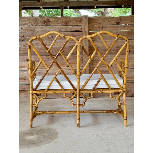 A stunning vintage rattan Chippendale fretwork settee showcasing an elegant geometric lattice back, gracefully curved...