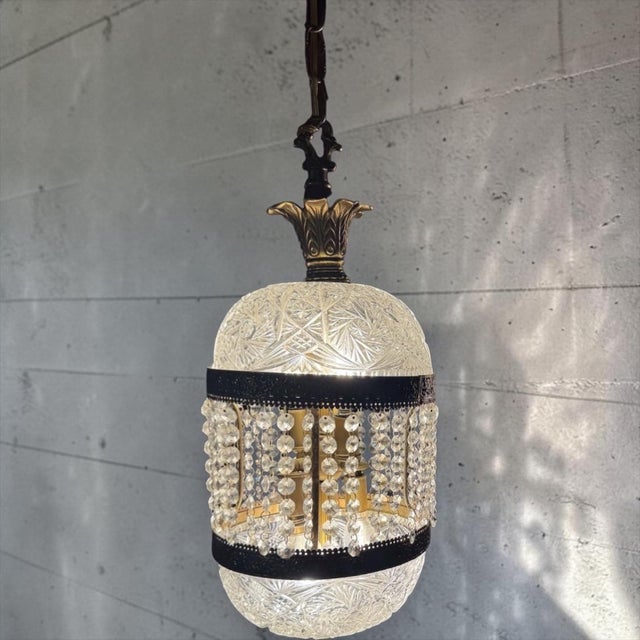 A dramatic vintage Hollywood Regency swag lamp featuring patterned clear glass, antiqued gold-tone metal detailing,...
