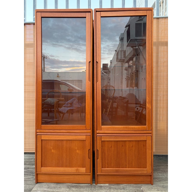 A Pair of Vintage Mid-Century Modern Danish Lighted Curio Display Cabinets by Sun Cabinet Co. Circa 1970s Features a clean...