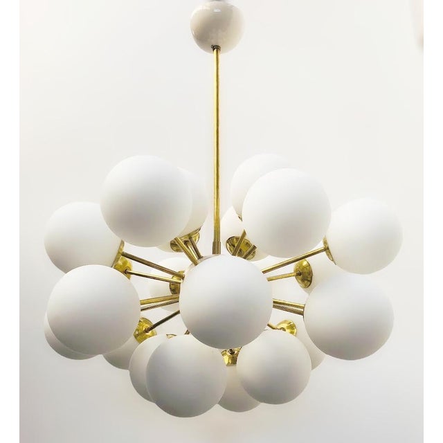 Italian oval shaped sputnik chandelier with 24 matte white Murano glass globes mounted on brass frame in unlacquered...