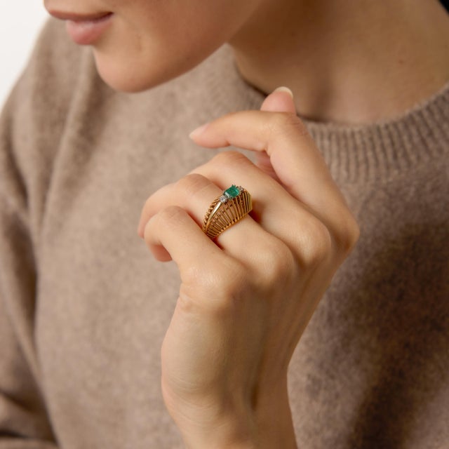 A refined jewel of the 1950s, this Mid Century ring highlights a vivid emerald cut emerald at its center, offering crisp...