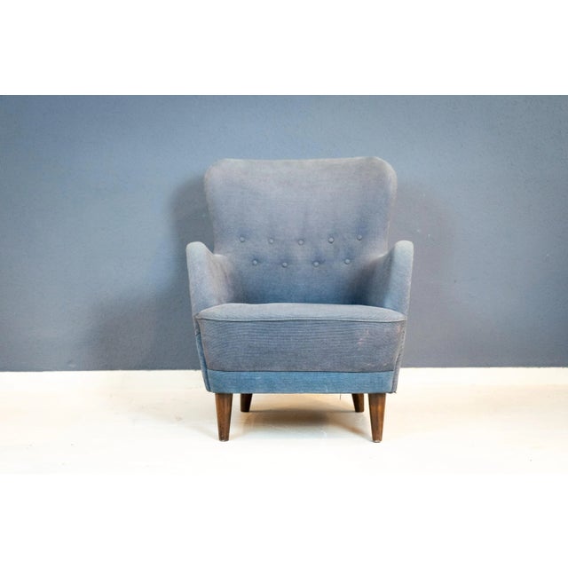 Solid wood frame with slender legs and a low seat upholstered in blue velvet. The high, gently sloping backrest is...