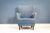 Solid wood frame with slender legs and a low seat upholstered in blue velvet. The high, gently sloping backrest is...