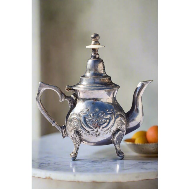 MOROCCAN SILVER TEAPOT Era: Mid-20th Century Origin: Morocco Material: Silver-plated Metal OVERVIEW: An ornate Moroccan...