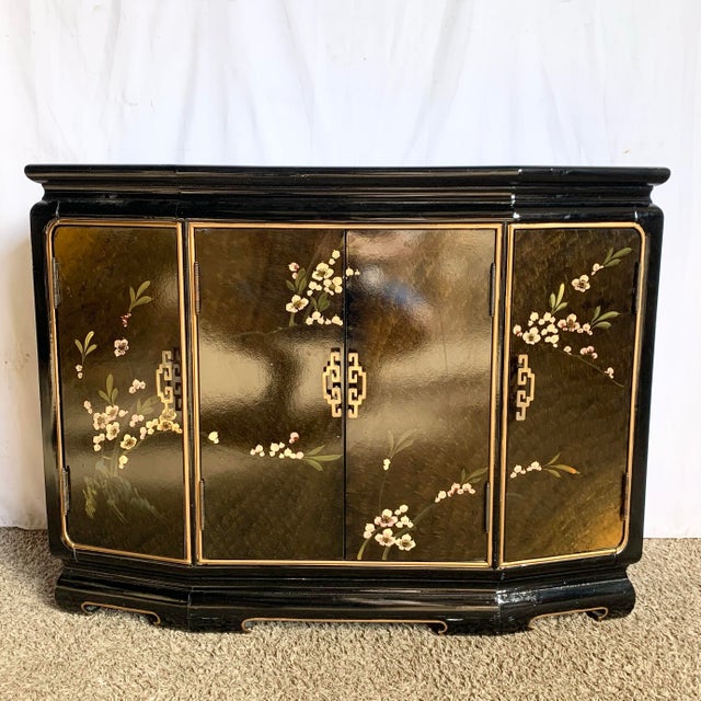 This Chinese black lacquered credenza showcases exquisite hand-painted floral detailing across its gracefully curved...