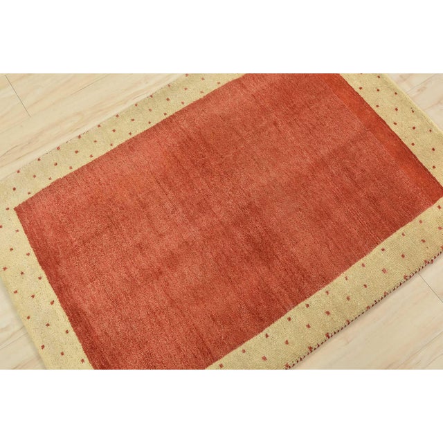 A contemporary Gabbeh rug hand-knotted with an all-wool pile on a cotton foundation. This finely woven area rug features a...