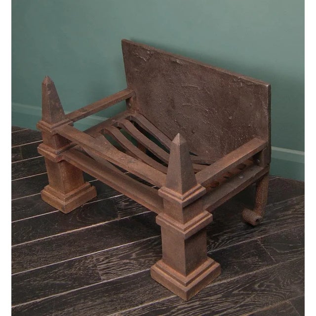 A wrought and cast-iron fire basket with obelisk finials set on sturdy square column and plinth legs. Swan’s nest fire...