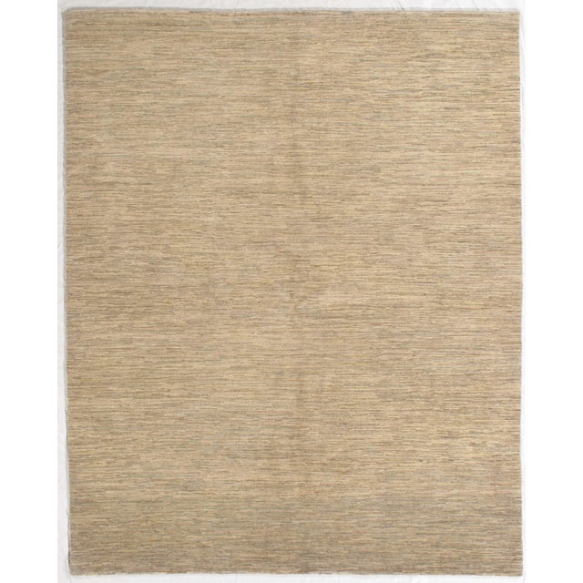 Hand-knotted Gabbeh rug featuring a minimalist, tonal field with fine horizontal striations in warm beige and soft taupe....