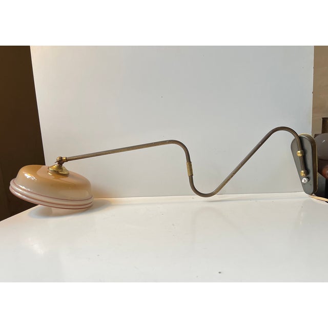 Fully adjustable wall lamp composed of an articulated brass 'body' and installed with a painted glass shade. It was made...