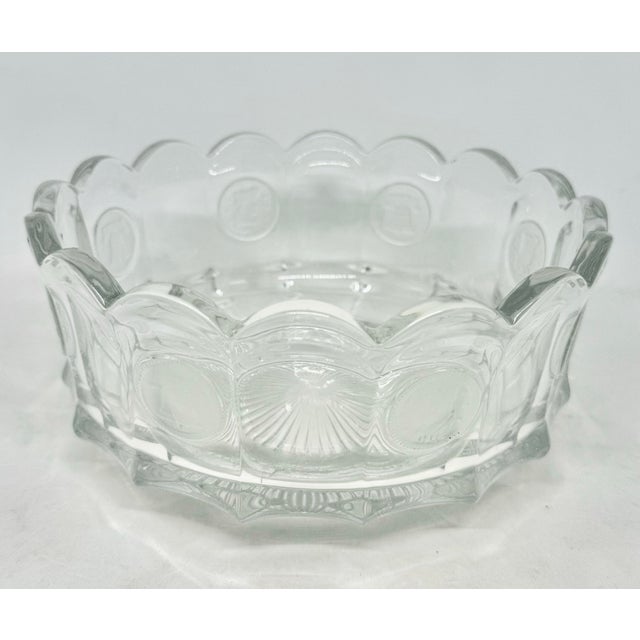 The 1960's Fostoria Clear Coin Glass Bowl with Liberty Bell 1886 Design is a vintage piece of pressed glass that features...