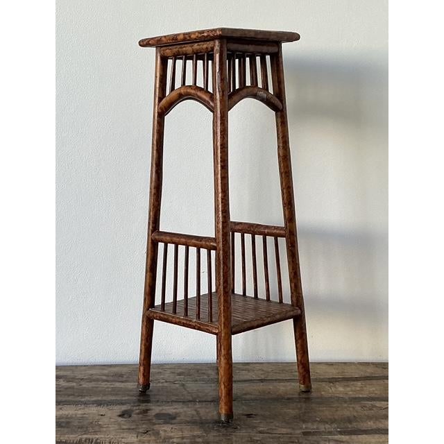 This elegant vintage pedestal stand is a masterclass in British Colonial and Hollywood Regency aesthetics, featuring a...