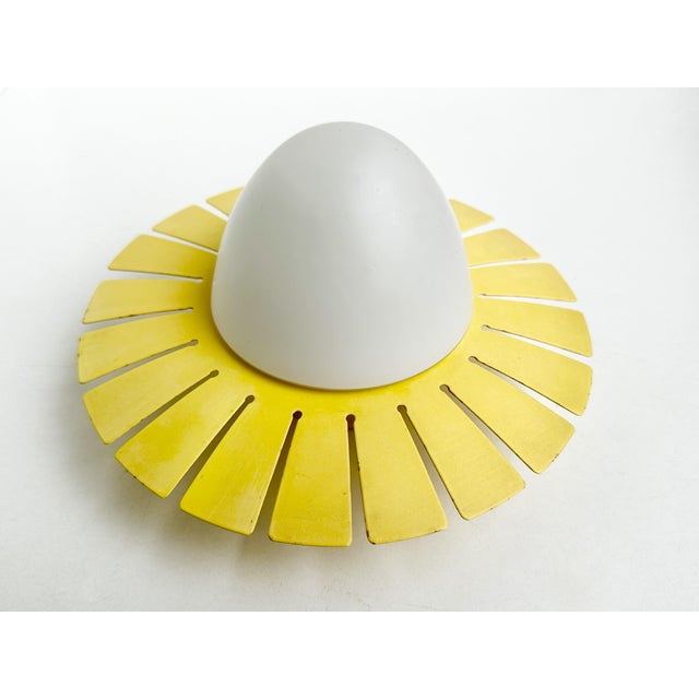 This elegant ceiling or wall light captivates with its characteristically abstract, minimalist, and cheerful sunburst...