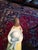 Pretty little girl figurine wearing a yellow dress with a red bow. Her white hat behind her has a blue ribbon. She has...