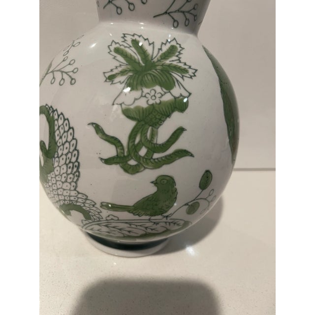 A festivity of nature, represented in greens and whites, is depicted on this two-toned round ceramic vase. Height is 8...