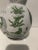 A festivity of nature, represented in greens and whites, is depicted on this two-toned round ceramic vase. Height is 8...