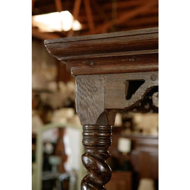 An antique oak tester bed with a molded and pierced carved cornice, a carved frieze and a geometrically fully paneled roof...