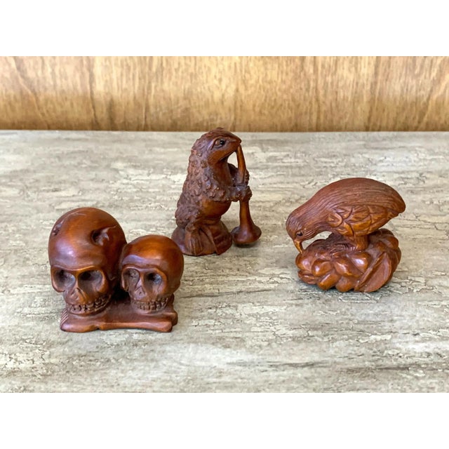 Set of three Japanese netsukes carved out of wood with a reddish stained finish, appear to be circa mid-20th century. One...