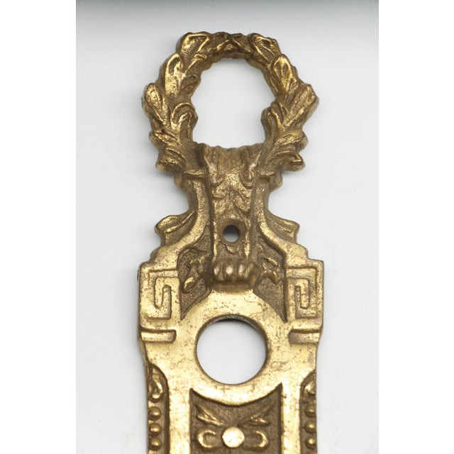 French style narrow cast brass door back plate with ribbon motif and keyhole. The original mounting screws are not...