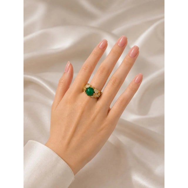 Stunning 18K yellow gold designer statement ring featuring a 5 carat natural oval cabochon emerald center, accented by...