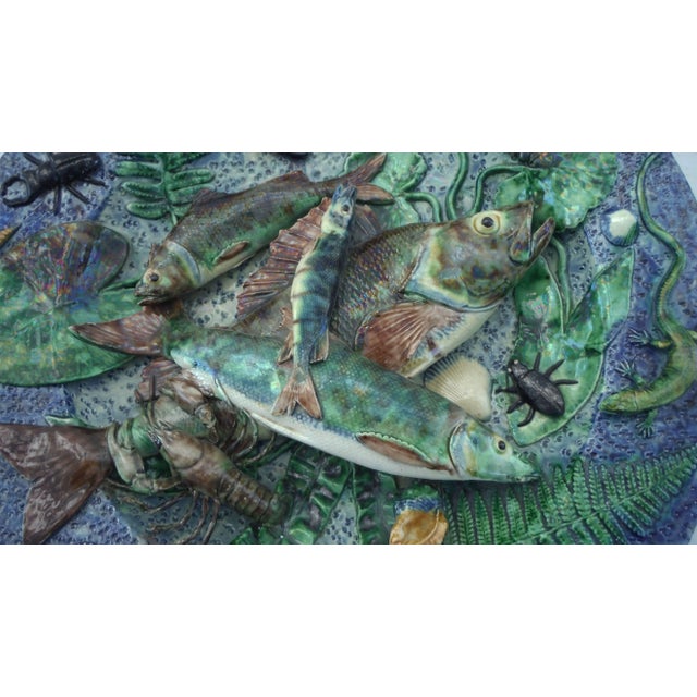 Large Palissy fishs wall platter on a blue background with bugs, butterfly, lizard, crawfish, shells, leaves as ferns. The...