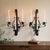 A substantial 1960s pair of black-painted iron wall candle sconces, each designed with three arms for standard taper...