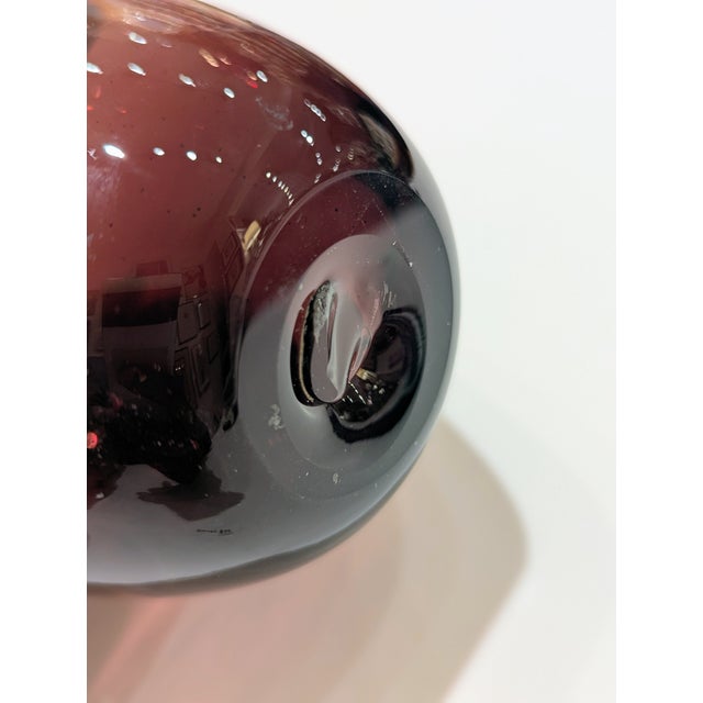 Sculptural art glass apple in deep purjple with clear applied stem. Dense, luminous form suited for desk or shelf display.