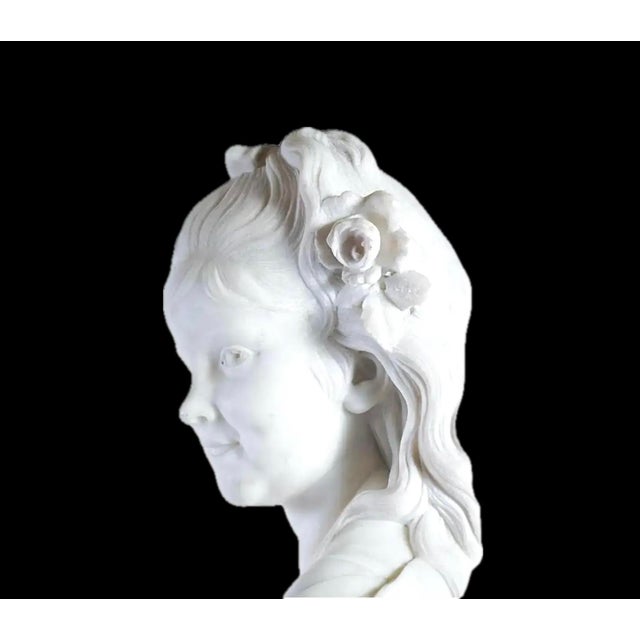 19th century Marble Bust Of A Young Girl in a graceful pose. The bust embodies the neoclassical ideals of the era,...