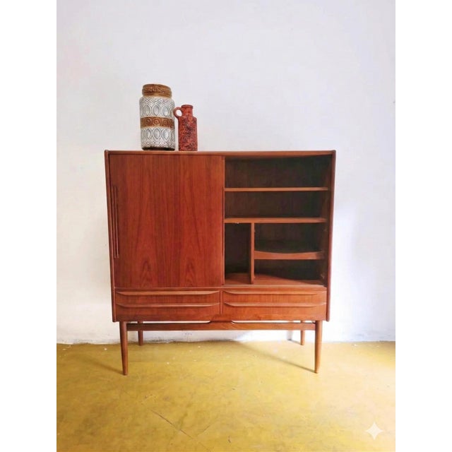 This elegant danish teak highboard from the 1960s is a versatile piece that exemplifies the functional beauty of mid-...
