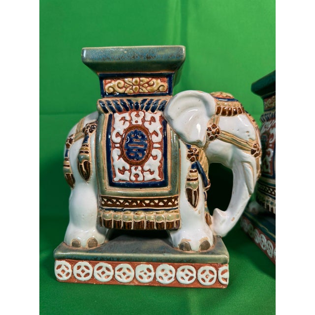 A matched pair of caparisoned elephant plant stands from a single mould, mid-20th century. Each carries an oval cobalt...