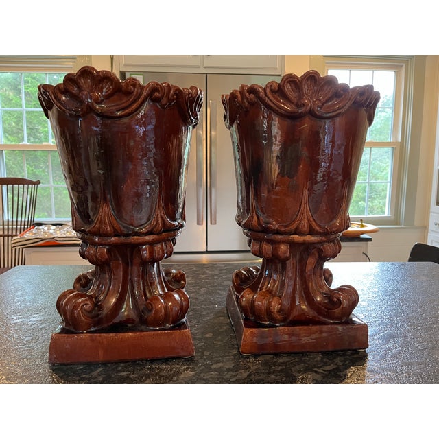 This striking pair of antique terracotta urns features a deep oxblood red glaze with a rich luster that enhances their...