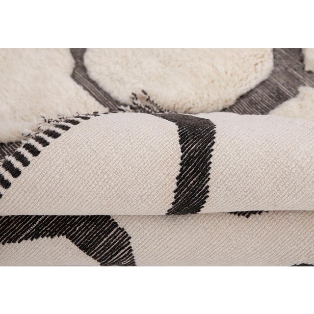 Hand-drawn circles, scattered like river stones. This hand-knotted Moroccan wool rug pairs a bold solid midnight black...