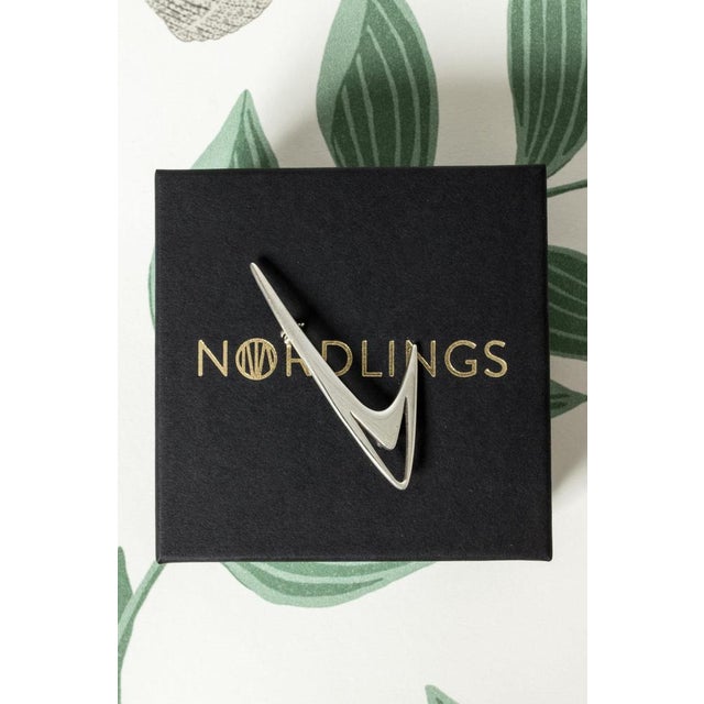 Sleek silver brooch by Poul Warmind, in a streamlined design with a cutout form. Weight 6 grams. This piece has an...