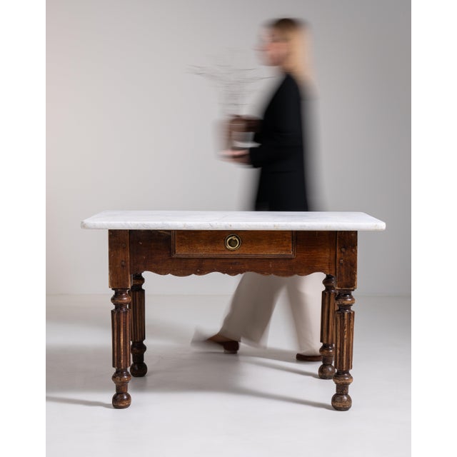 A robust butcher-style table featuring a solid base and marble top, combining practicality with refined material contrast....