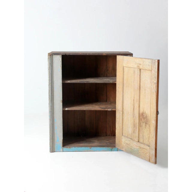 This is an antique rustic farmhouse cabinet. The primitive cupboard features a single paneled door that opens to three...