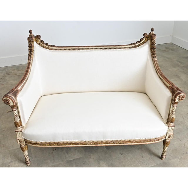 A glorious Louis XVI style canapé-settee from 19th century France, with parcel gilt details to enhance the neoclassical...