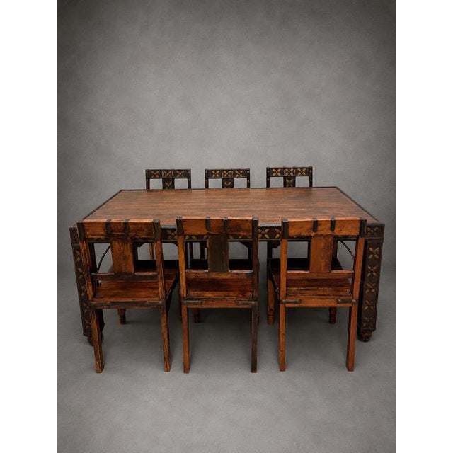 A stunning handcrafted antique Indian dining set consisting of a large solid wood dining table and six matching chairs....
